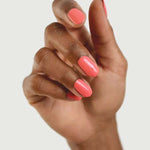 A hand with medium brown skin displays neatly manicured nails painted in Sienna Byron Bay Laughter, a glossy pink shade by Sienna Byron Bay, against a plain light background.