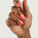 A hand with medium brown skin displays neatly manicured nails painted in Sienna Byron Bay Laughter, a glossy pink shade by Sienna Byron Bay, against a plain light background.