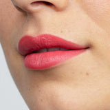 Close-up of smooth lips wearing Antipodes Moisture Boost Natural Lipsticks 4g in coral pink, with an even, moisturizing finish. Text below reads South Pacific Coral.