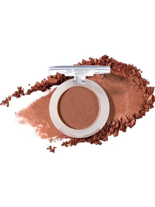 An open round compact of 100% Pure Fruit Pigmented® Eye Shadow 2g by 100% Pure displays its pressed powder, with loose vegan eyeshadow scattered around it on a clean white background.