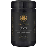 A black container of Superfeast Jing Powder 100g features gold and white text, a gold emblem, and is labeled as an energy tonic for adrenal support; it contains a tonic herb blend in oral powder form.