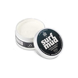 A 100g tin of Surfmud Ocean Addicts Sunscreen SPF 30 sits open on a white background, showing the mineral cream inside with the lid placed beside it.
