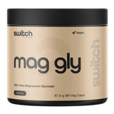 A beige and black plastic tub of Switch Nutrition Mag Gly, featuring a black lid and a beige label with black text, on a solid white background.