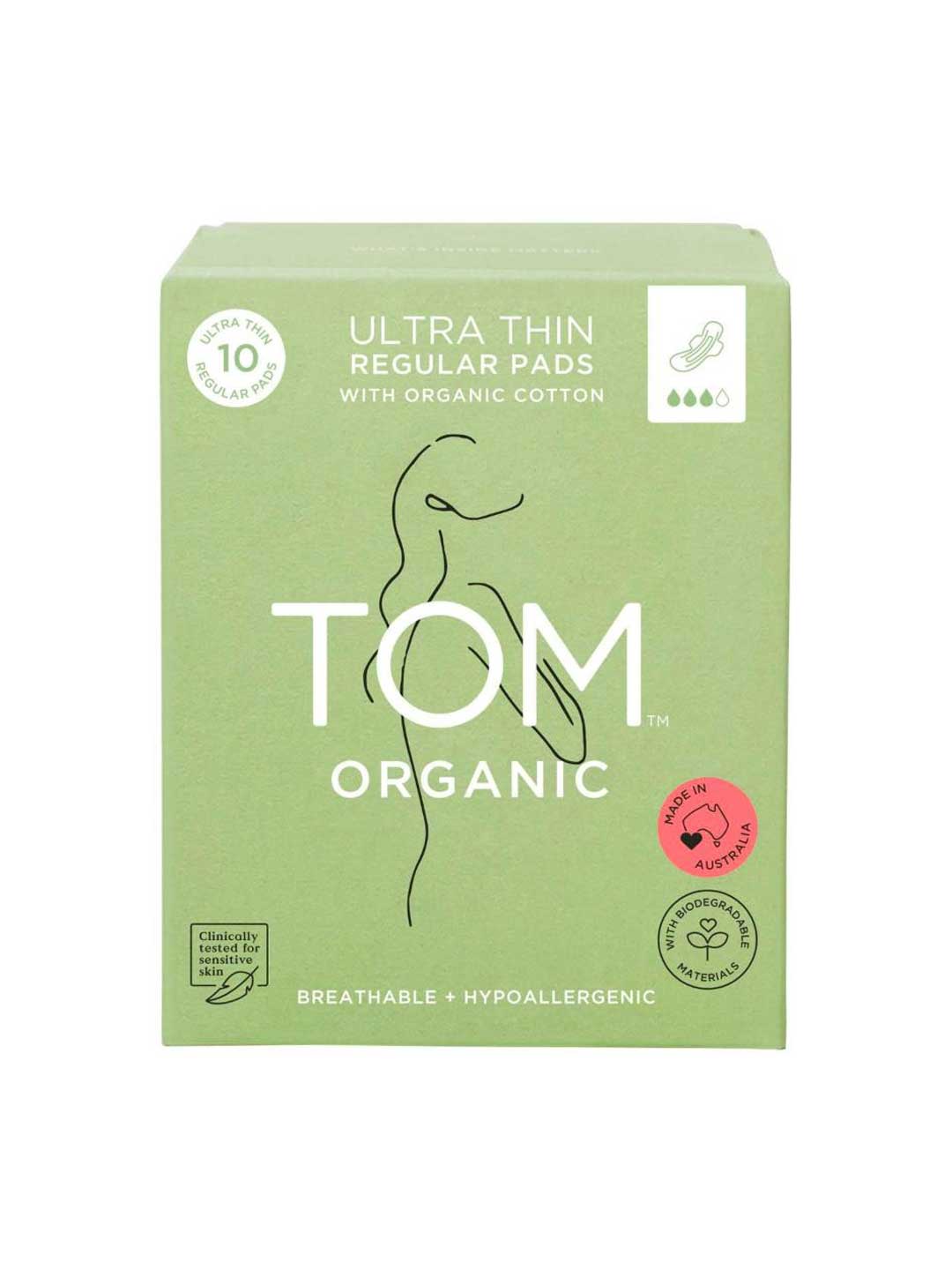 A green box of TOM Organic Pads Regular 10pk, made with organic cotton, features a minimalist woman line drawing, highlights hypoallergenic and biodegradable pads, and displays a pink certified organic label.