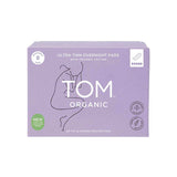 A lavender box of TOM Organic Pads Ultra Thin Overnight 8pk, made from biodegradable organic cotton, features minimalist line art of a woman plus organic and vegan certification icons.