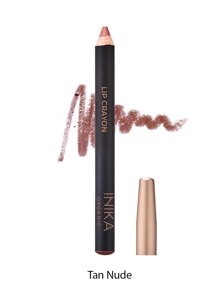 A tan nude INIKA Organic Lip Crayons 6.7g stands upright with its cap off, tip exposed. Behind it is a swatch of the long-lasting liner and "INIKA Organic Lip Crayon" with "Tan Nude" below on the product.