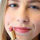 A smiling person holds a tube of Luk Beautifood Lip Nourish Lipsticks 3g in a pink shade near their lips. "Tangerine Pomegranate" appears at the bottom of the image.