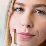 A woman with light skin applies Luk Beautifood Lip Nourish Lipsticks 3g in Tea Rose, holding the mauve-pink tube near her face. The words "Tea Rose" appear at the bottom of the image.