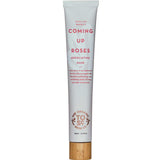 A white tube of The Organic Skin Co Coming Up Roses Exfoliating Mask 60ml, with pink text and a wooden cap, contains rose and bamboo stem extract. The label highlights this organic exfoliating mask.
