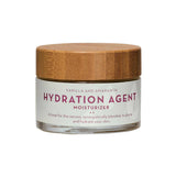The Organic Skin Co Hydration Agent 50ml is an organic moisturizer in a glass jar with a wooden lid, designed to plump and hydrate dry skin with its synergistic Vanilla and Amaranth formula.
