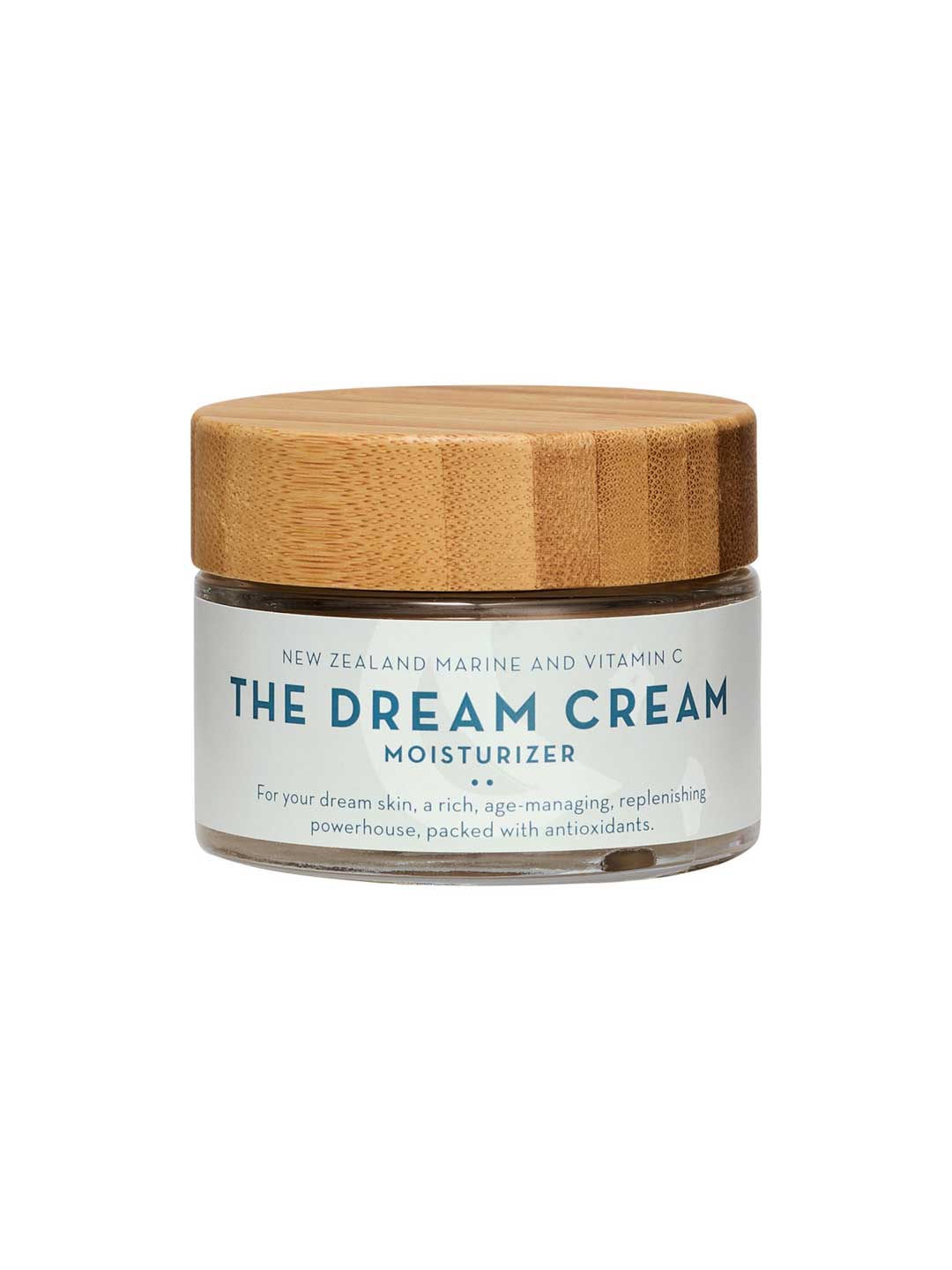 A glass jar of The Organic Skin Co The Dream Cream with a wooden lid, this organic New Zealand moisturizer features marine and vitamin C for age management, skin renewal, and antioxidant-rich replenishing.