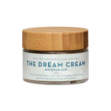 A glass jar of The Organic Skin Co The Dream Cream with a wooden lid, this organic New Zealand moisturizer features marine and vitamin C for age management, skin renewal, and antioxidant-rich replenishing.