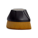 The Three Warriors Beauty Buff Brush features dense brown bristles and a short, rounded black handle for streak-free self-tan application. Shown against a white background, it’s perfect as a self-tan applicator.