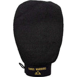 The Three Warriors Eco Friendly Exfoliating Mitt is a black glove with a textured surface, gold branding on the cuff, and a small loop—ideal for prepping skin for tanning or removing fake tan.