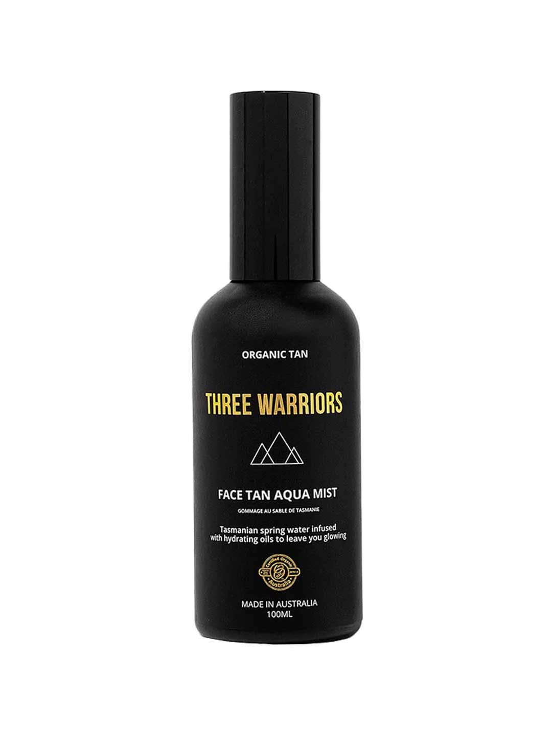 Three Warriors Face Tan Aqua Mist 100ml comes in a black bottle with gold and white branding, featuring a geometric logo. This vegan, organic face tan mist provides a natural-looking glow and is made in Australia.