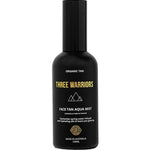 Three Warriors Face Tan Aqua Mist 100ml comes in a black bottle with gold and white branding, featuring a geometric logo. This vegan, organic face tan mist provides a natural-looking glow and is made in Australia.