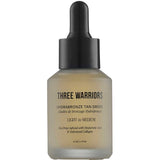 A 30 ml bottle of Three Warriors Hydrabronze Tan Drops with a black dropper cap, labeled "HydraBronze Tan Drops, Light to Medium," designed for gradual tanning.
