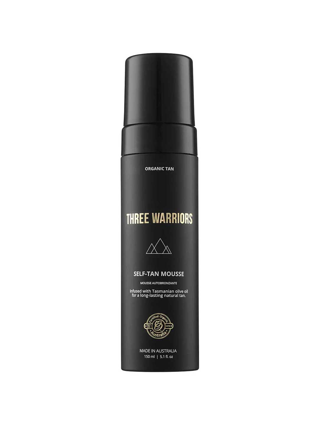 A black bottle of Three Warriors Self Tanning Mousse 150ml with gold and white text and a pump dispenser. This organic self-tan uses natural DHA and Tasmanian olive oil for a flawless Australian glow.