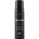 A black bottle of Three Warriors Self Tanning Mousse 150ml with gold and white text and a pump dispenser. This organic self-tan uses natural DHA and Tasmanian olive oil for a flawless Australian glow.
