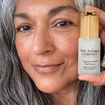 Woman holding The Jojoba Company Transformative Eye Serum near her face