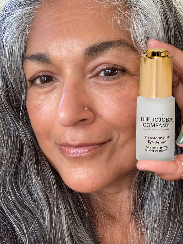 Woman holding The Jojoba Company Transformative Eye Serum near her face