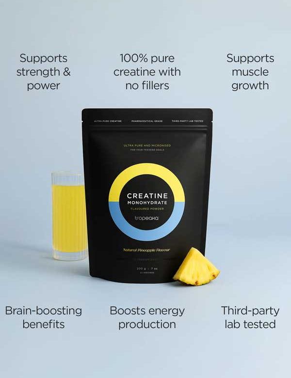 A black pouch of Tropeaka Creatine Monohydrate Pineapple 200g sits beside a glass of yellow pineapple drink and a pineapple slice, with text showing benefits such as muscle strength, energy, brain support, purity, and lab testing.
