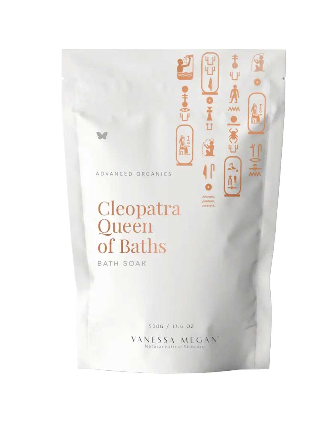 A white pouch labeled Vanessa Megan Cleopatra Queen of Baths Bath Soak/Scrub with gold Egyptian-style symbols. This 500g vegan milk bath soak, from their advanced organics line, is designed for radiant skin.