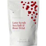 A white pouch labeled Vanessa Megan Love Scrub Sea Salt & Rose Petal 500g, featuring red rose petals at the top and highlighting a natural exfoliator with sea salt scrub benefits. Weight: 500g / 17.6 oz.