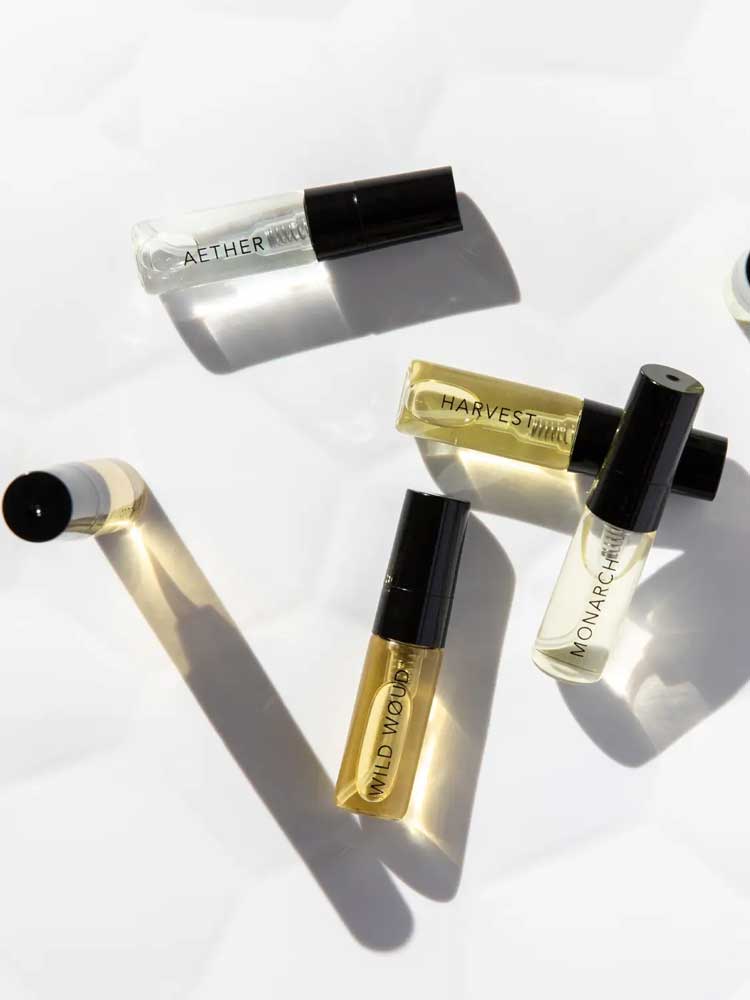 Six small 3ml glass perfume vials from Vanessa Megan’s 100% Natural Mini Eau de Parfum Collection lie on a white surface, each botanical fragrance capturing the essence of nature in an elegant set.