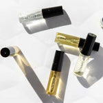 Six small 3ml glass perfume vials from Vanessa Megan’s 100% Natural Mini Eau de Parfum Collection lie on a white surface, each botanical fragrance capturing the essence of nature in an elegant set.