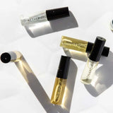 Six small 3ml glass perfume vials from Vanessa Megan’s 100% Natural Mini Eau de Parfum Collection lie on a white surface, each botanical fragrance capturing the essence of nature in an elegant set.