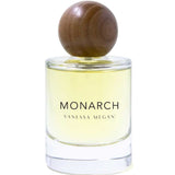 The Vanessa Megan Monarch 100% Natural Eau de Parfum 50ml features a clear glass bottle with yellow liquid and a round wooden cap, showcasing an elegant, floral-musk scent crafted with clean perfumery principles.