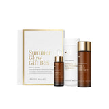 The Vanessa Megan Summer Glow Gift Pack includes three natural skincare essentials—a dropper bottle, a cylindrical bottle, and a white exfoliator container with collagen boosting gel—displayed in front of a chic white and gold box.