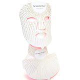 The Vanessa Megan The Butterfly Effect Medical-Grade Silicone LED Face & Neck Mask Set, in white and gold, covers the face and neck on a mannequin. Gold dotted lines radiate outward, evoking a luxurious at-home skincare experience.