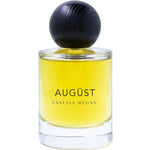 The Vanessa Megan Augüst 100% Natural Eau de Parfum (50ml) is a clear glass bottle with yellow liquid, a large round dark cap, and contains botanical perfume inspired by Australian bush scents.
