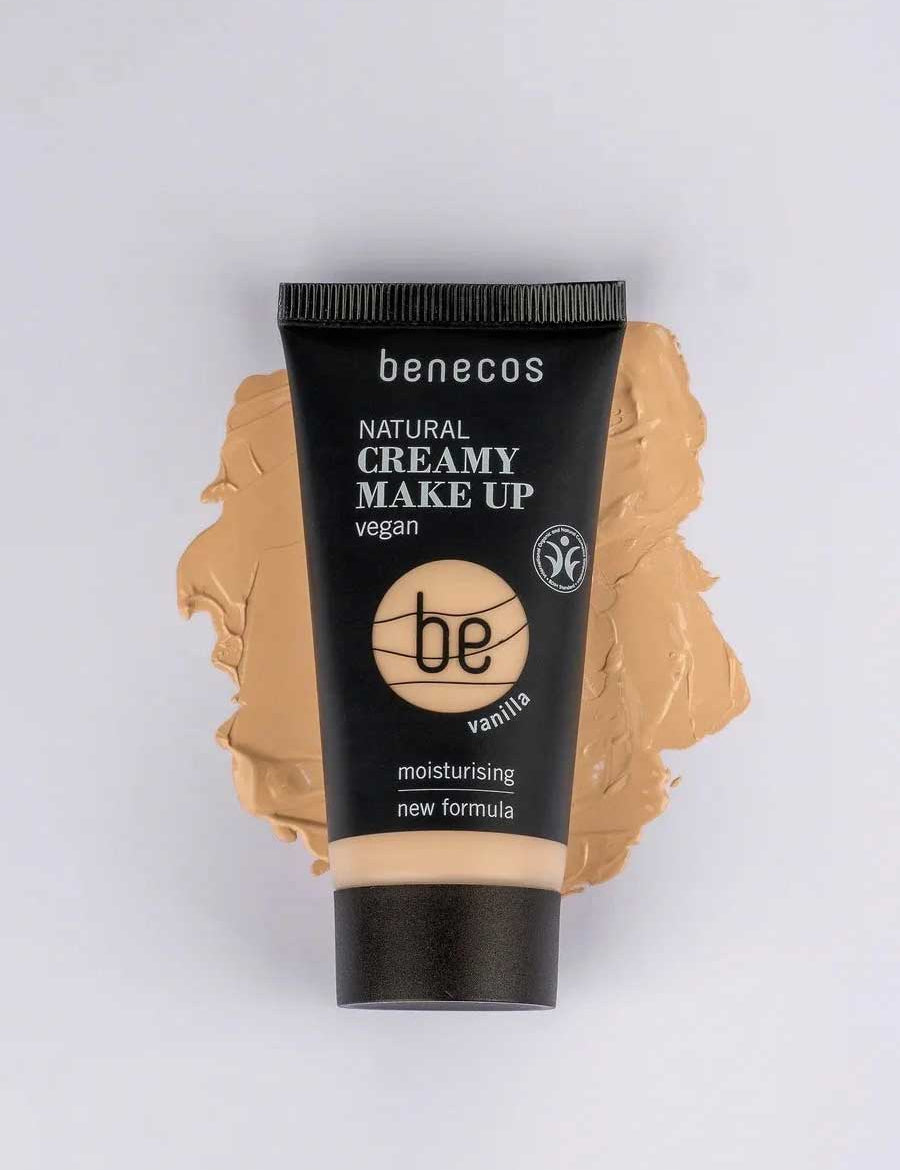 A tube of Benecos Natural Creamy Makeup 30ml in vanilla lies on a foundation smear, showcasing features like vegan makeup, moisturising foundation, and a new formula highlighted on the packaging.
