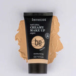 A tube of Benecos Natural Creamy Makeup 30ml in vanilla lies on a foundation smear, showcasing features like vegan makeup, moisturising foundation, and a new formula highlighted on the packaging.