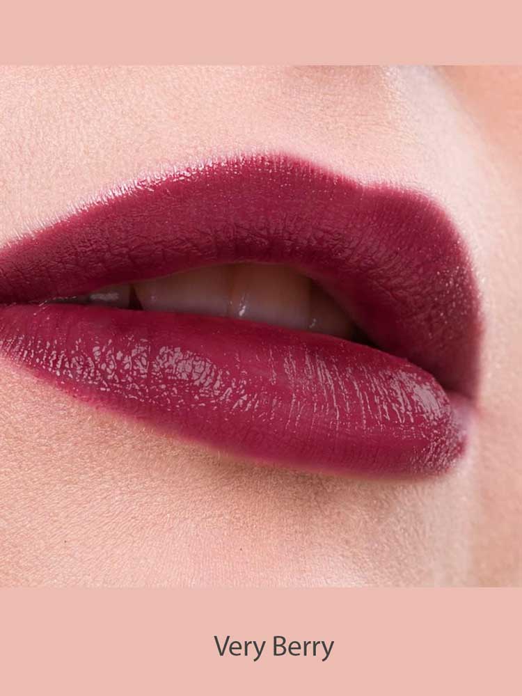 Close-up of lips wearing Benecos MAT Lipsticks 4.5 in a berry shade with a natural matte finish, slightly parted to reveal teeth. Pale pink skin and background. Text below reads "Very Berry.