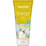 A 200ml yellow tube of Weleda Energy Shower Gel Ginger, with natural fragrance and an illustration of two people by a riverside with greenery and red flowers. The label notes energizing ginger for a refreshing shower experience.