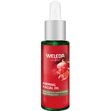 A green glass bottle of Weleda Pomegranate Firming Facial Oil 30ml with a white dropper cap and red label featuring a pomegranate image, highlighting pomegranate seed oil for reducing lines and nourishing mature skin.