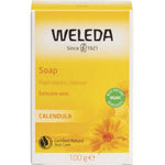 A yellow and white box of Weleda Soap Bar Calendula 100g for sensitive skin, with a sunflower graphic, certification logos, and text highlighting its organic, plant-based ingredients.
