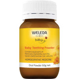 A brown bottle of Weleda Baby Teething Powder 60g with a yellow label, white lid, and chamomile flowers. This homeopathic oral powder is designed for babies.