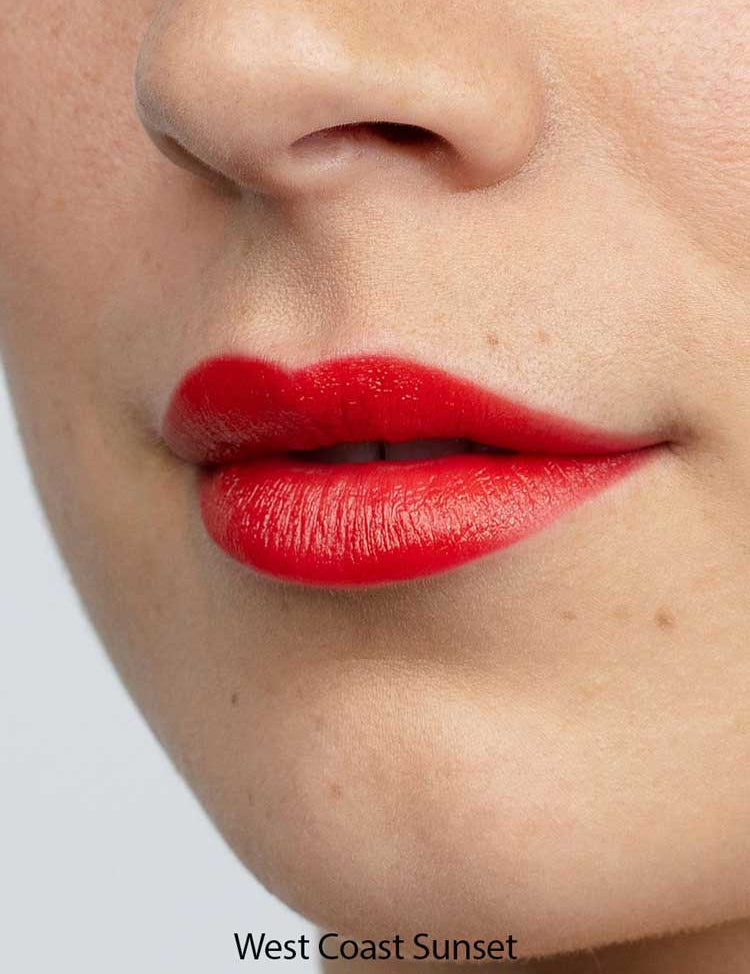 A close-up of lips wearing Antipodes Moisture Boost Natural Lipsticks 4g in a vibrant red shade, showing smooth skin. "West Coast Sunset" appears at the bottom of the image.