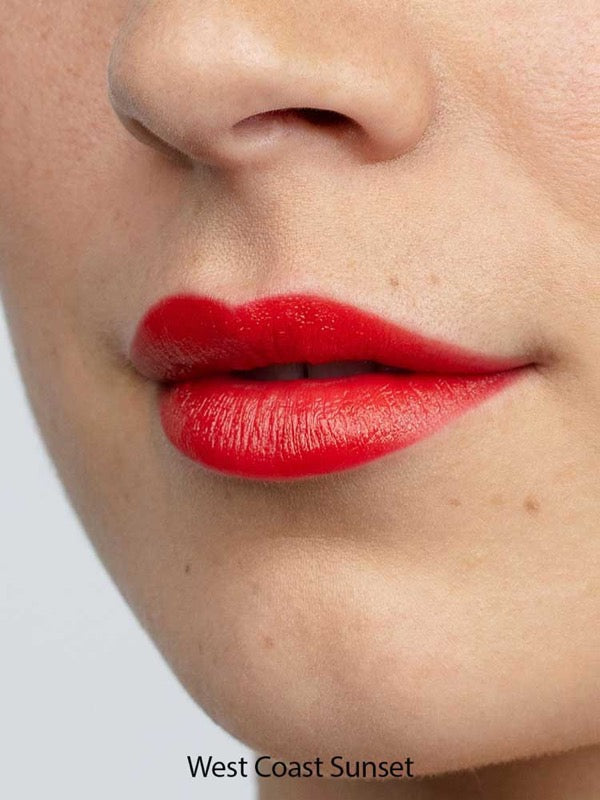 A close-up of lips wearing Antipodes Moisture Boost Natural Lipsticks 4g in a vibrant red shade, showing smooth skin. "West Coast Sunset" appears at the bottom of the image.