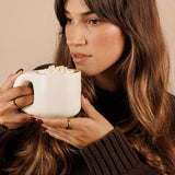 Woman sipping Nutra Naturals Collagen White Hot Chocolate Salted Caramel