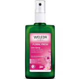 A green bottle of Weleda Floral Fresh Deodorant Spray - Wild Rose 100ml has a pink floral label noting its natural, aluminium-free formula.