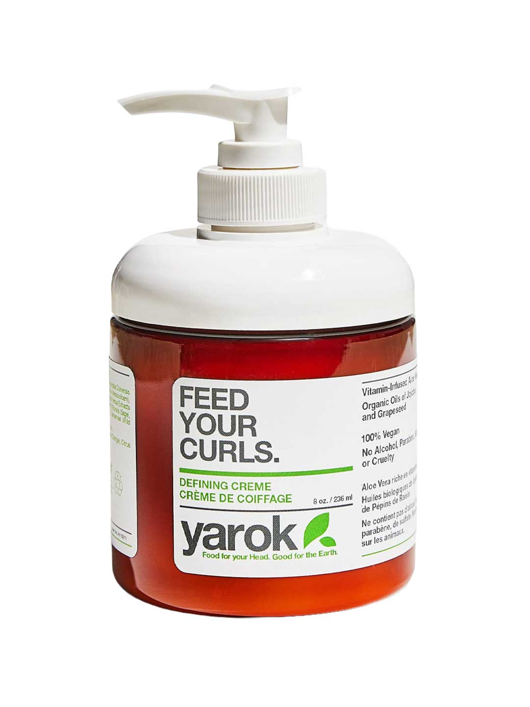A bottle of Yarok Defining Creme on a white background, featuring a white pump dispenser, a translucent white cap, and a white label with green and black text over a reddish-brown bottle body.