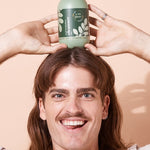 A bit Hippy Face and Body Cleanser balanced above a smiling man's head