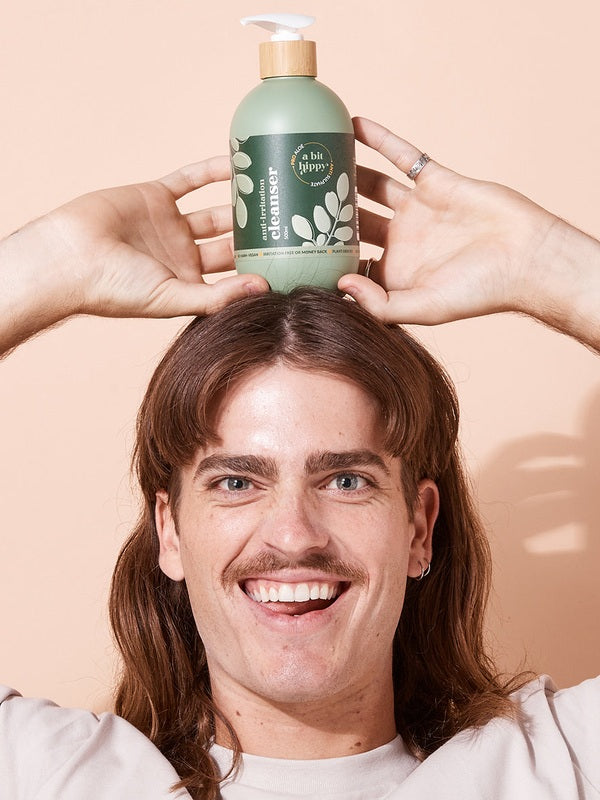 A bit Hippy Face and Body Cleanser balanced above a smiling man's head