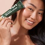 A bit Hippy Blemish Cream held beside a woman's face